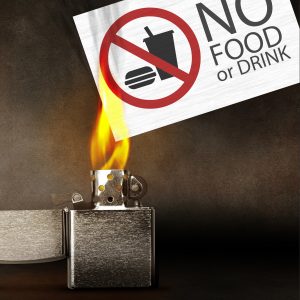 lighter setting a no food or drink sign on fire